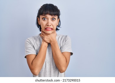 Young hispanic woman wearing casual t shirt over blue background shouting and suffocate because painful strangle. health problem. asphyxiate and suicide concept. 
