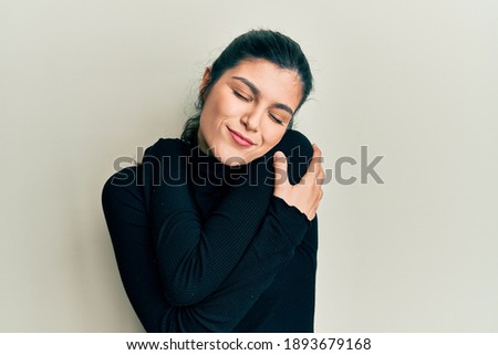 Young hispanic woman wearing casual clothes hugging oneself happy and positive, smiling confident. self love and self care 