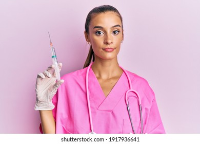 Young Hispanic Woman Wearing Doctor Stethoscope Holding Syringe Thinking Attitude And Sober Expression Looking Self Confident 