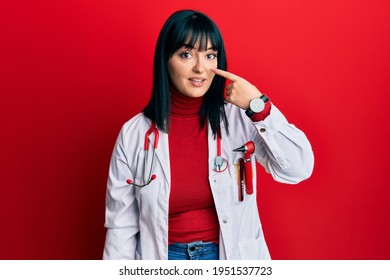 Young Hispanic Woman Wearing Doctor Uniform And Stethoscope Pointing With Hand Finger To Face And Nose, Smiling Cheerful. Beauty Concept 