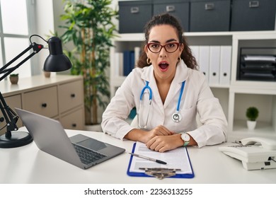 Young hispanic woman wearing doctor uniform and stethoscope afraid and shocked with surprise and amazed expression, fear and excited face.  - Shutterstock ID 2236313255