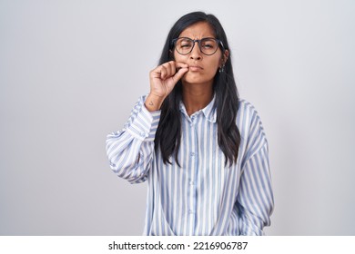 Young Hispanic Woman Wearing Glasses Mouth And Lips Shut As Zip With Fingers. Secret And Silent, Taboo Talking 