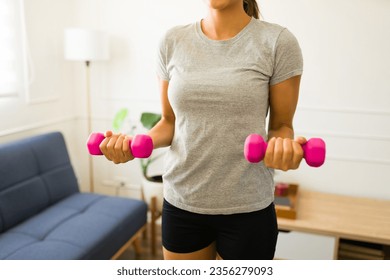 Young hispanic woman wearing a gray mock-up t-shirt for a design copy space exercising lifting dumbbells weights - Powered by Shutterstock