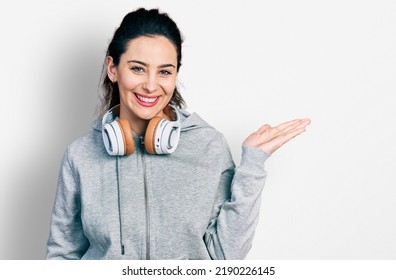 Young Hispanic Woman Wearing Gym Clothes, Using Headphones And Smart Watch Smiling With A Happy And Cool Smile On Face. Showing Teeth. 