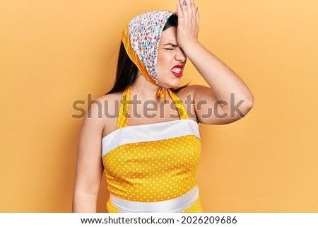 Young hispanic woman wearing pin up style surprised with hand on head for mistake, remember error. forgot, bad memory concept. 