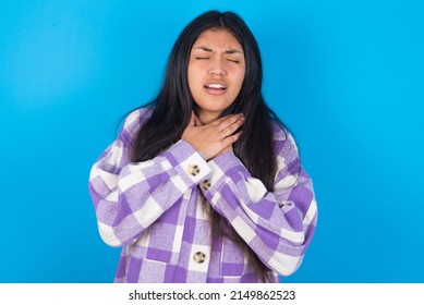 young hispanic woman wearing plaid shirt over blue background shouting suffocate because painful strangle. Health problem. Asphyxiate and suicide concept.