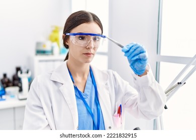 Young Hispanic Woman Wearing Scientist Uniform Holding Insect With Tweezers At Laboratory