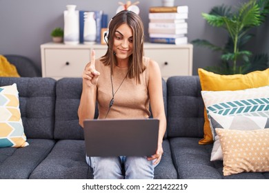 Young Hispanic Woman Working From Home Wearing Operator Headset Smiling With An Idea Or Question Pointing Finger With Happy Face, Number One 