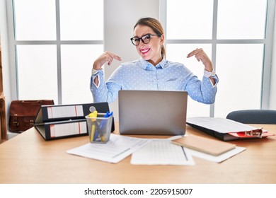 Young hispanic woman working at the office wearing glasses looking confident with smile on face, pointing oneself with fingers proud and happy.  - Shutterstock ID 2205915007