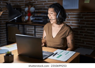 Young hispanic woman working at the office at night angry and mad screaming frustrated and furious, shouting with anger. rage and aggressive concept.  - Shutterstock ID 2310699253