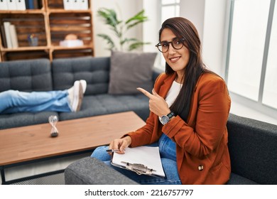 Young Hispanic Woman Working As Psychology Counselor Pointing With Hand Finger To The Side Showing Advertisement, Serious And Calm Face 