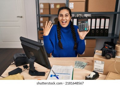 Young Hispanic Woman Working At Small Business Ecommerce Holding Calculator Scared And Amazed With Open Mouth For Surprise, Disbelief Face 