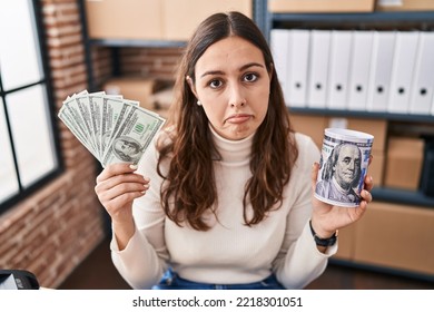 Young Hispanic Woman Working At Small Business Ecommerce Holding Money And Piggy Bank Depressed And Worry For Distress, Crying Angry And Afraid. Sad Expression. 