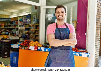 Young hispanic worker wearing apron standing with arms crossed gesture at the fruit store.