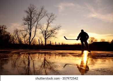 Young hockey player on natural ice during calm winter sunset