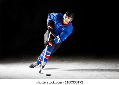 Young Hockey Player With Stick And Puck Skating On Rink In Attack Against Dark Background