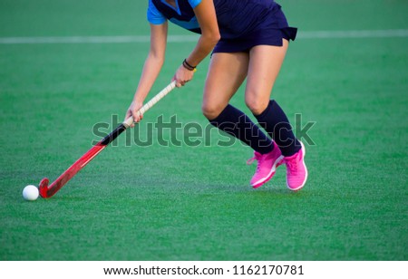Young hockey player woman with ball in attack playing field hockey game
