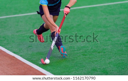 Young hockey player woman with ball in attack playing field hockey game