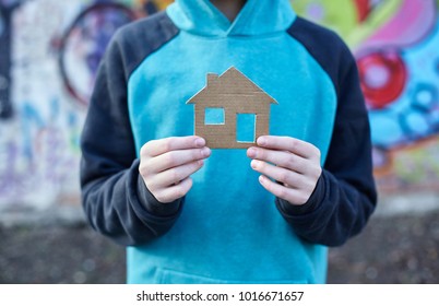 Young Homeless Boy Holding A Cardboard House