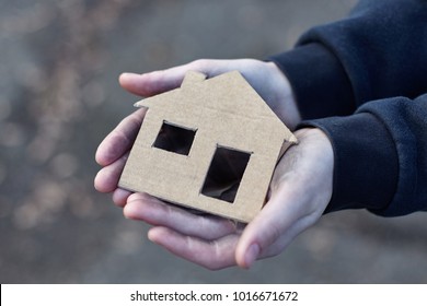 young homeless boy holding a cardboard house