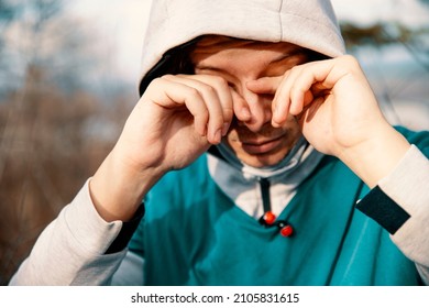 Young hooded Man outdoor have irritation of eye, itchy and dry. Sportsman have Allergic reaction on jogging and sensitive eyes. Copy space
