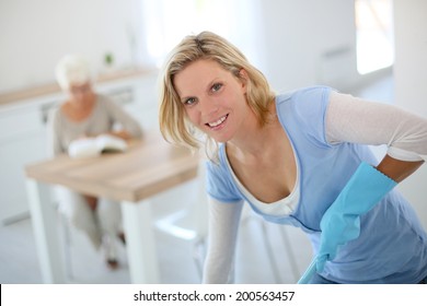 Young Housekeeper Cleaning Floor In Senior Home