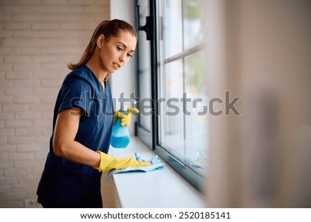 Young housekeeper using spray bottle and cloth while cleaning up. Copy space. 