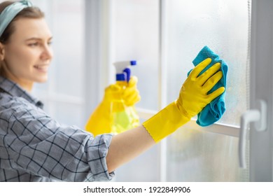 Young Housekeeper Washing Window Glass With Rag And Spray Detergent, Selective Focus. Positive Millennial Woman Doing Professional House Cleaning, Providing Sanitary Service, Closeup