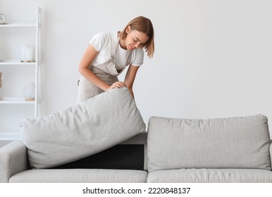 Young Housewife Adjusting Sofa At Home