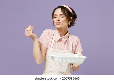 Young housewife chef cook baker woman in pink apron show cookies biscuits on baking form making okay taste delight sign, savoring, delicious isolated on pastel violet background. Cooking food concept.