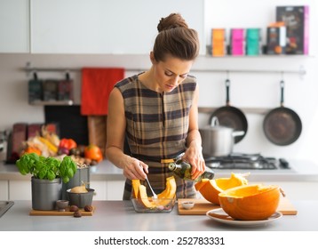 Young housewife cooking pumpkin in kitchen