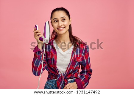 Young housewife with iron, pink background