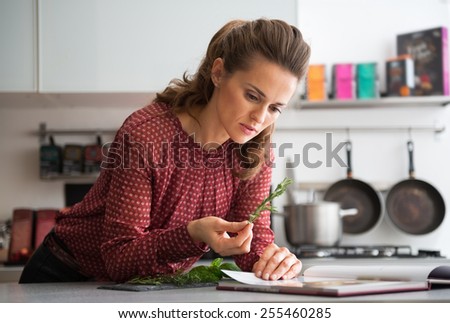 Young housewife studying fresh spices herbs in kitchen