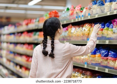 Young housewife takes food from shelve. Showcase at background. Back view. Concept of shopping in supermarket and consumerism. - Shutterstock ID 2238718773