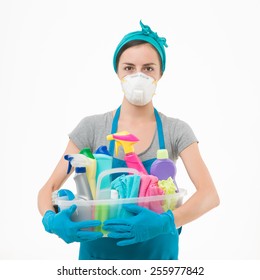young housewife wearing protection mask, holding cleaning supplies against white background