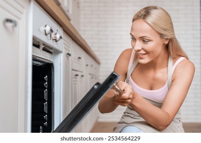 Young housewife woman in casual clothes puts casserole in baking dish in oven cooking sniff delicious scent food in light kitchen at home alone Healthy diet bakery lifestyle concept. - Powered by Shutterstock