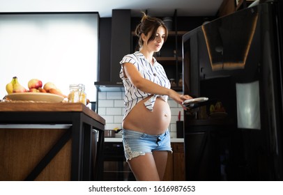 Young Hungry Pregnant Woman Looking For Food In Refrigerator