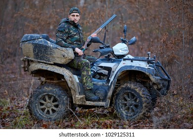 Young Hunter On A Quad Bike Searching For Game In The Forest