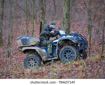 Young Hunter On A Quad Bike Searching For Game In The Forest