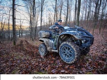 Young Hunter On A Quad Bike Searching For Game In The Forest