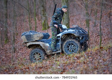 Young Hunter On A Quad Bike Searching For Game In The Forest