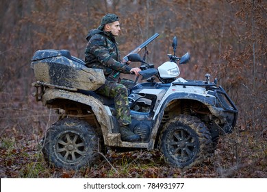 Young Hunter On A Quad Bike Searching For Game In The Forest