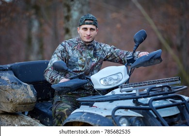 Young Hunter On A Quad Bike Searching For Game In The Forest