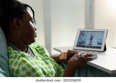 Young ill patient using tablet for telemedicine video call with doctor in hospital ward bed. Black person talking to specialist on online conference technology with digital gadget - Shutterstock ID 2019258299