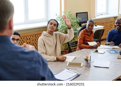 Young immigrant Black student attending language classes sitting at table raising hanf to ask teacher question - Shutterstock ID 2160229231