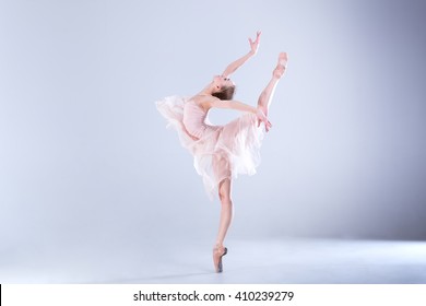 Young and incredibly beautiful ballerina is posing and dancing in a white studio full of light. The photo greatly reflects the incomparable beauty of a classical ballet art.