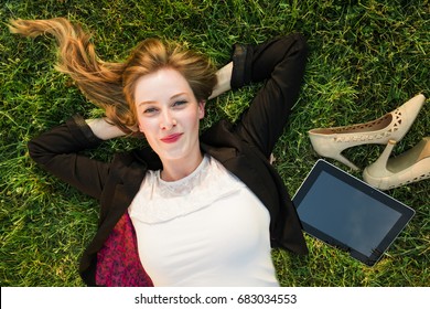 Young Independent Woman Relaxing On Grass In Park