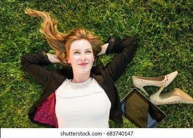 Young Independent Woman Relaxing On Grass In Park