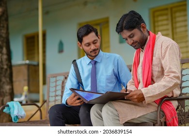 Young India Bank Officer Completing Paper Work With Farmer At His Home.