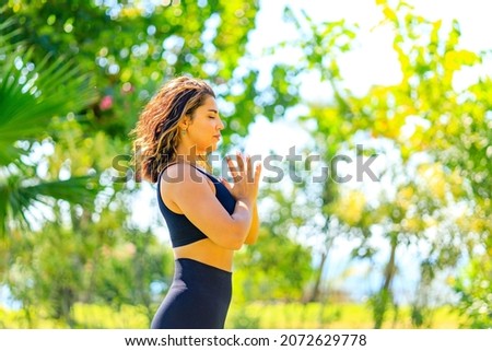 Young indian attractive woman practicing yoga , deep calm breathing outdoors in summer green park